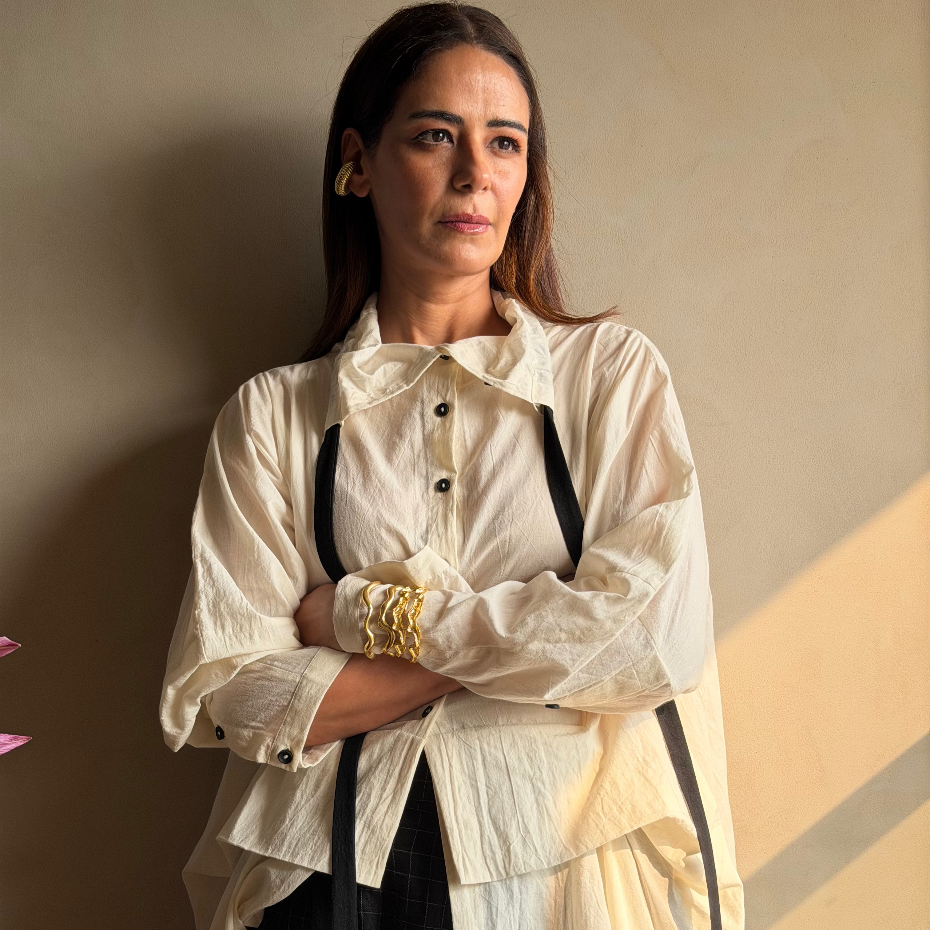Mona Singh wearing a gold cuff from nihiraa against a beige wall